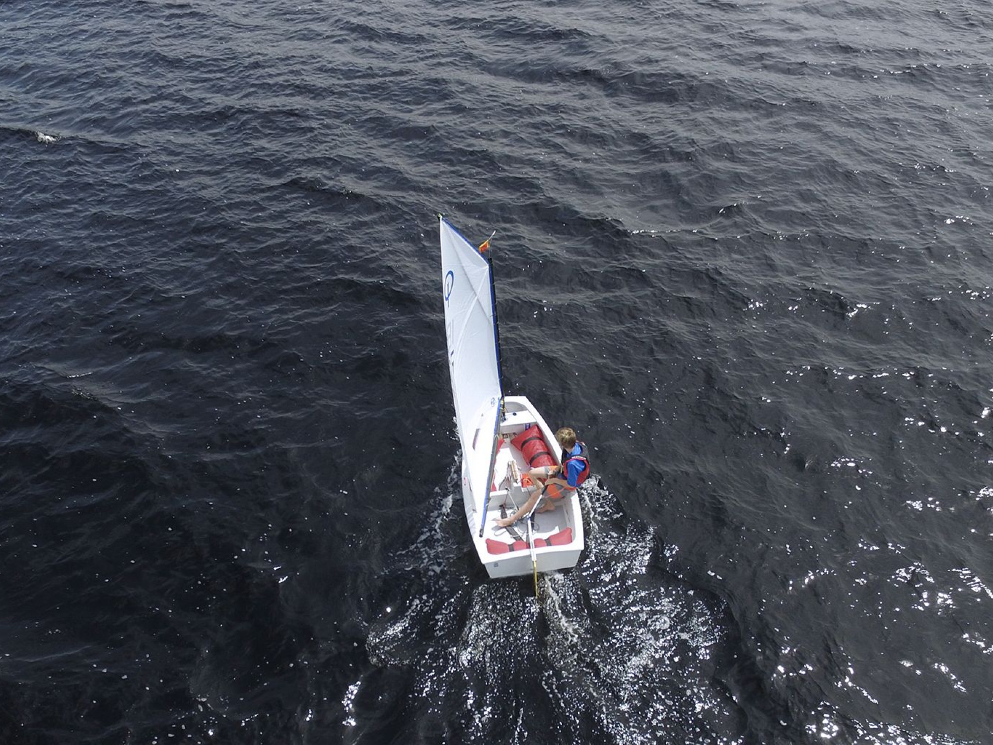 Aerial of young boy in Opti sailboat